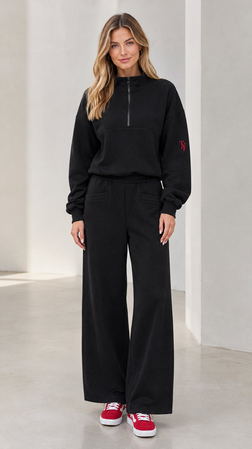 Front full view of woman wearing black half-zip pullover and wide-leg sweatpants lounge set