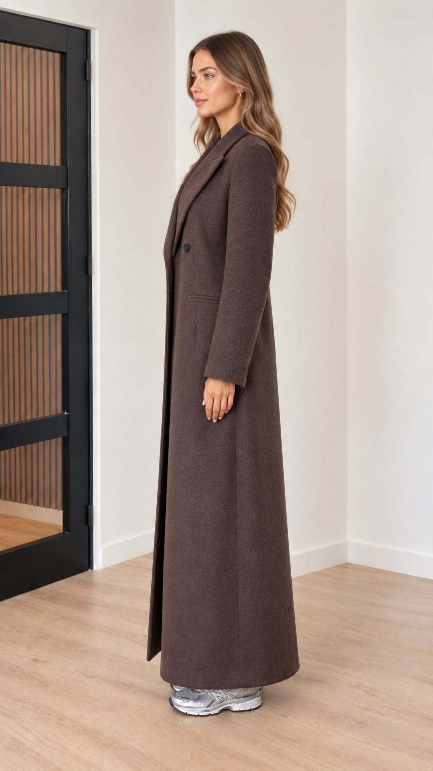 Side profile view of woman wearing long chocolate brown overcoat