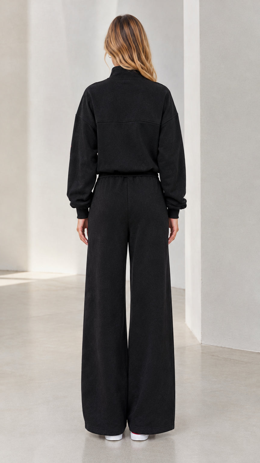 Back view of woman wearing black relaxed wide-leg sweatpants and half-zip top set