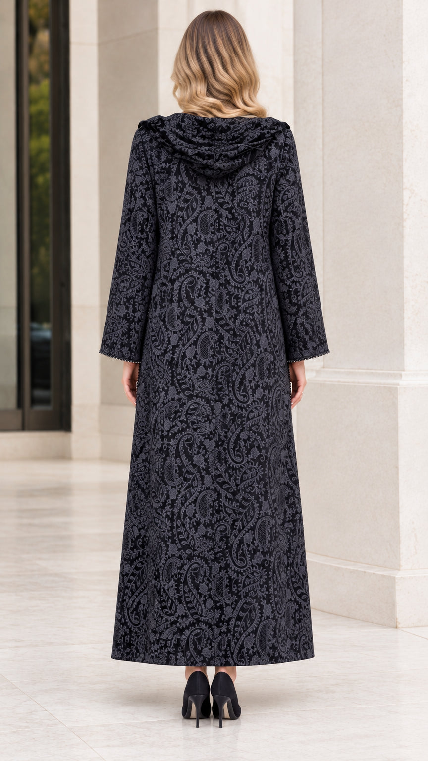 Back full-length view of woman wearing hooded black paisley jacquard duster coat