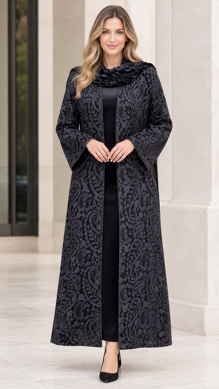 Front full-length view of woman wearing black paisley jacquard maxi duster coat with matching draped scarf
