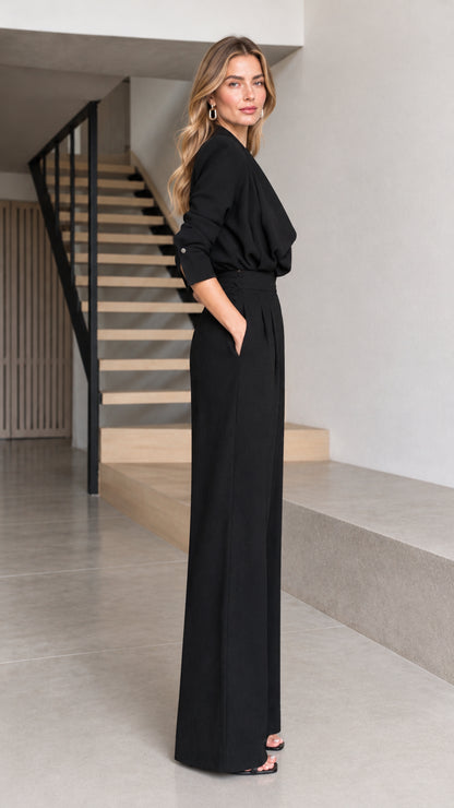 Side full view of woman wearing black wide-leg jumpsuit with side pockets