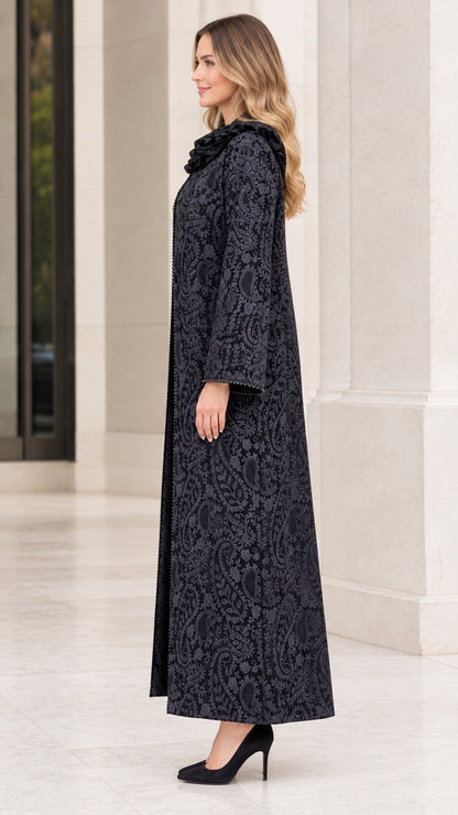 Side profile view of woman wearing black paisley jacquard maxi duster coat with beaded accents