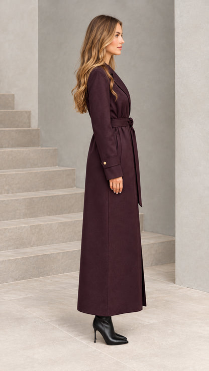 Side profile view of woman wearing burgundy full-length belted overcoat