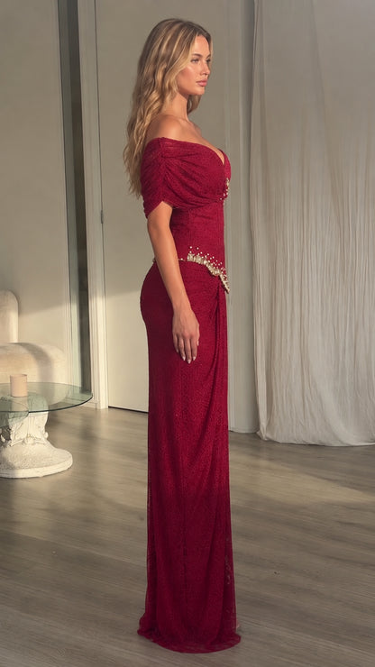 Side profile view of model wearing burgundy off-shoulder formal evening gown