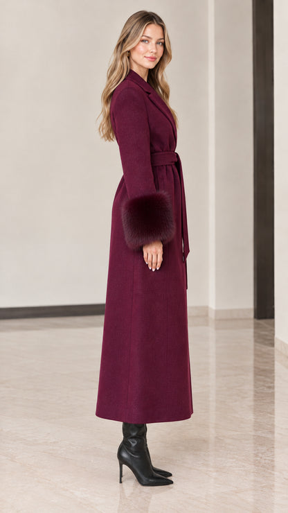 Side profile of model in burgundy floor-length belted winter coat with fur sleeve trims