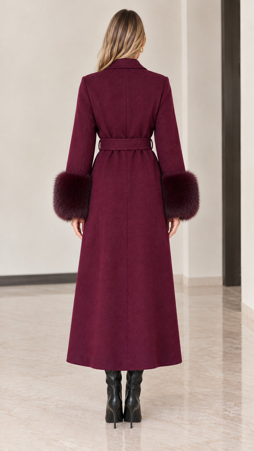 Back view of model in full-length burgundy overcoat showing tailored seams and belt