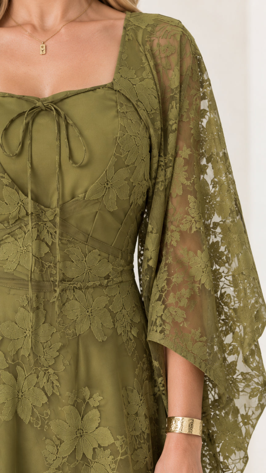 Close-up detail of olive green tie-front square neckline and floral lace texture