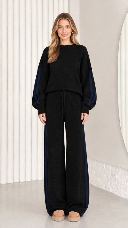 Front view of model wearing black knit two-piece lounge set with navy side stripes