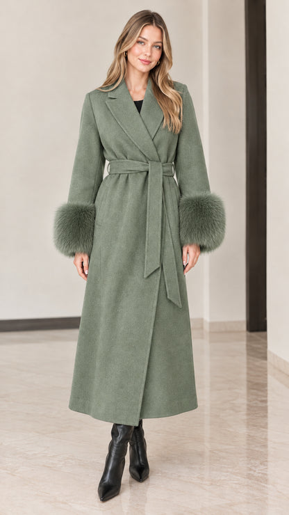 Front view of model wearing sage green maxi wrap coat with plush green faux fur cuffs