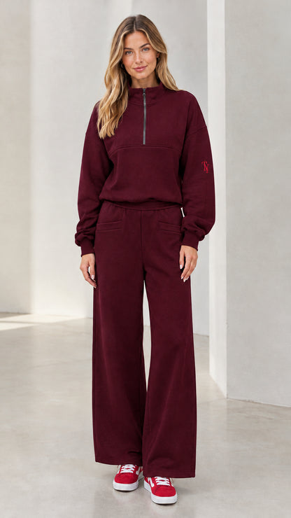 Front view of woman wearing burgundy half-zip pullover and wide-leg lounge set
